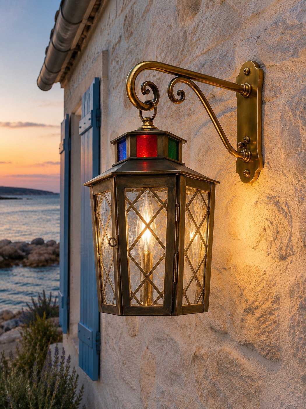 Lanterne murale en laiton sur potence à volutes, vitraux colorés et bougie, vue sur la mer