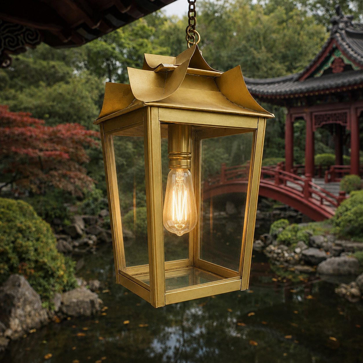 Lanterne suspendue en laiton à toit relevé, ampoule allumée, au-dessus d'un bassin de jardin